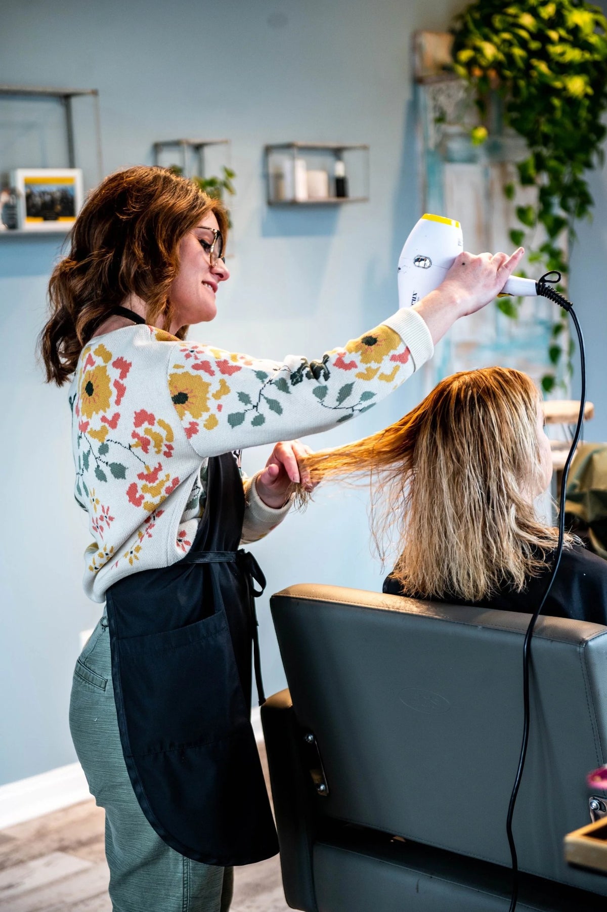 Stylist blow drying a guest's long balayage hair at the salon at SALT Salon + Spa, Antioch IL